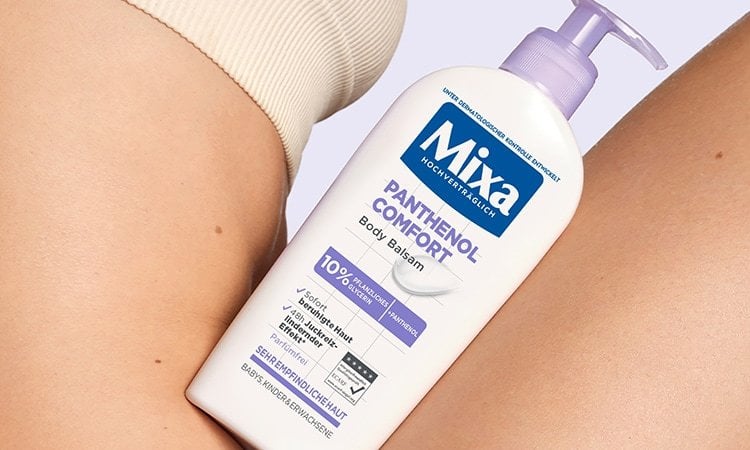 Der Panthenol Comfort Body Balsam von Mixa lehnt am Körper einer Frau.