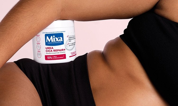 Die Urea Cica Repair+ Allzweckcreme von Mixa lehnt am Arm einer Frau.