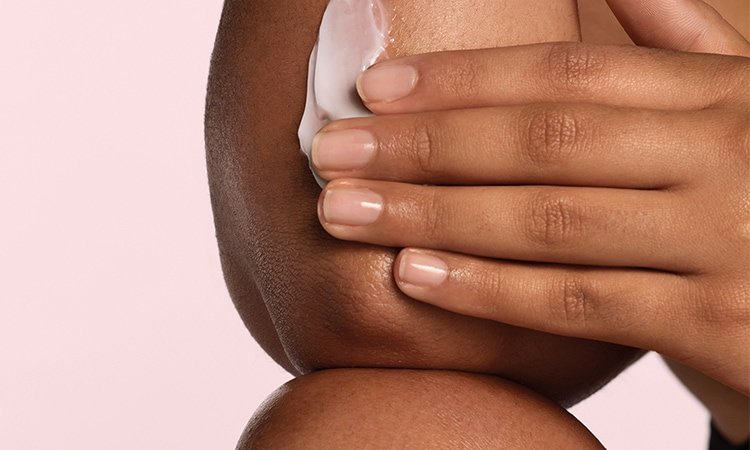 Eine Person trägt einen Klecks Bodylotion zur Feuchtigkeitspflege auf den Unterarm auf.