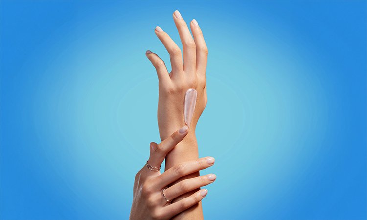 Zwei gepflegte Hände mit einem Klecks Handcreme auf dem linken Handrücken
