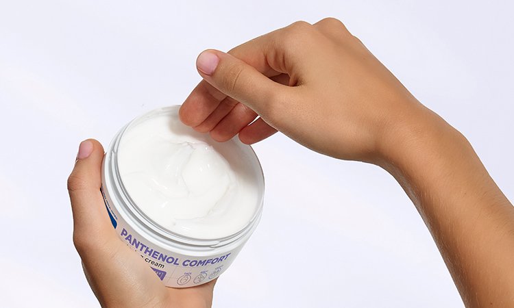 Eine Person fasst in eine Tube Creme Eine Person fasst in eine Tube Creme