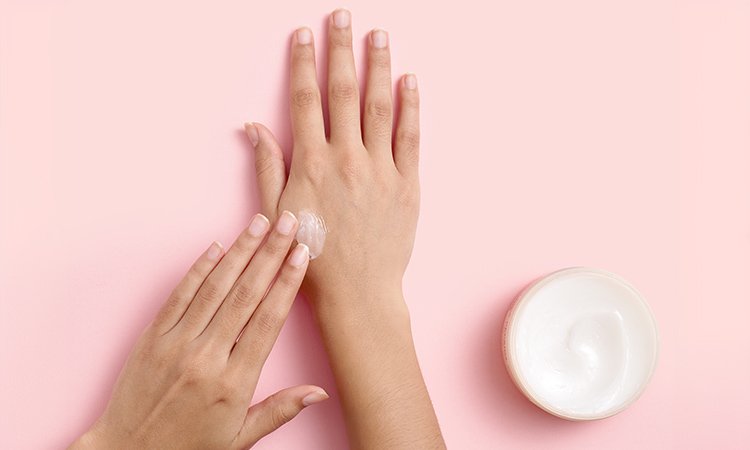 Eine Person cremt ihre rechte Hand ein Eine Person cremt ihre rechte Hand ein