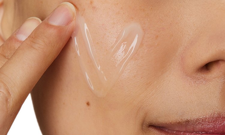 Eine junge Frau verteilt eine Creme auf ihrer Wange