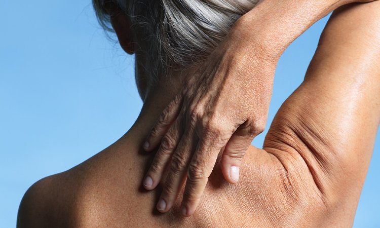 Eine Frau fährt mit ihrer Hand über ihren Rücken