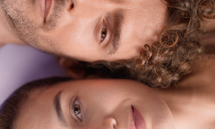 Nahaufnahme zweier Gesichter mit klarer, ebenmäßiger Haut vor lila Hintergrund