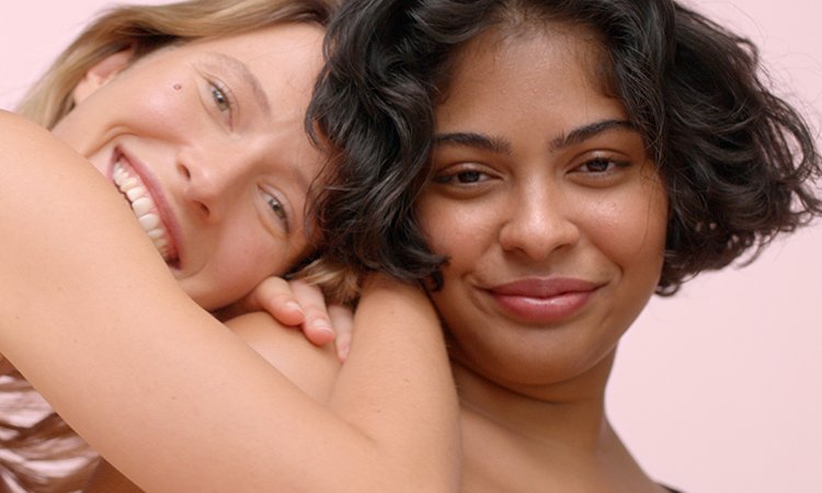 Produktabbildungen von MIXA Eine Frau mit blonden Haaren legt ihr strahlendes Gesicht und ihren Arm auf der Schulter einer Frau mit kurzen, dunkelbraunen Haaren, die ebenfalls lächelt, ab