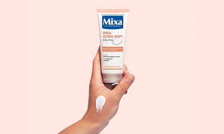 Eine Person hält die Shea Ultra Soft Body Milk mit einer Hand, auf der bereits ein Klecks Creme zu sehen ist