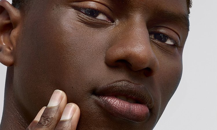 Ein Mann fasst sich mit der Hand an die Wange