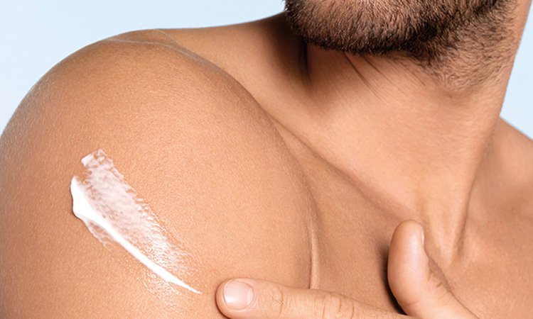 Ein Mann trägt sich Creme auf seinen rechten Oberarm auf