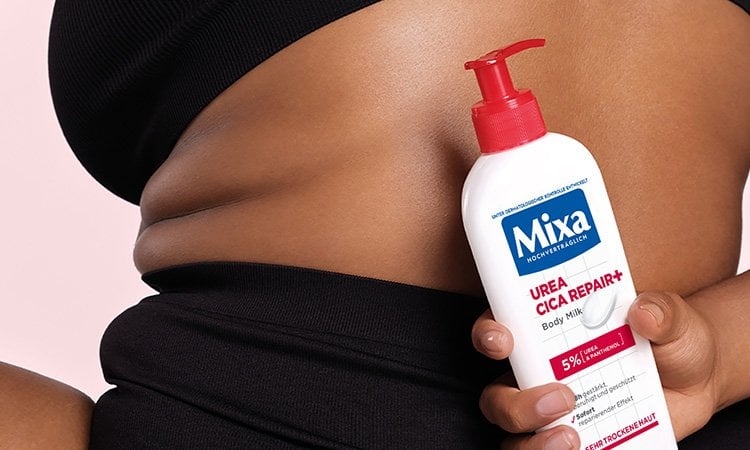 Eine Frau hält die Mixa Urea Cica Repair+ hinter ihrem Rücken