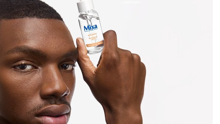 Mann hält sich das Mixa Serum mit Vitamin C neben sein Gesicht