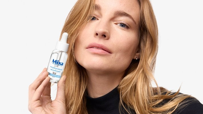 Frau hält Mixa Serum Anti-Trockenheit in der Hand neben ihr Gesicht